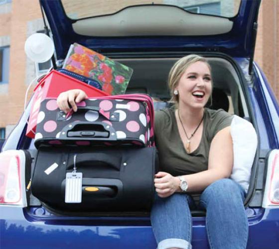 Student sitting in back of car full of luggages 