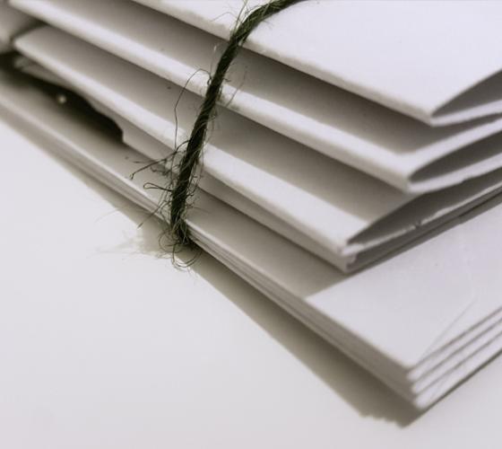 cut off image of white folders and enveloped piled with a black string wrapped around them
