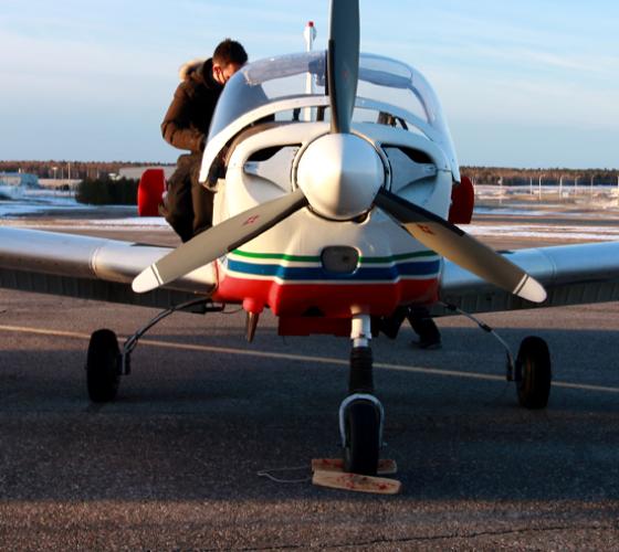 plane parked at the Hangar with a student on it checking the safety requirements before a flight