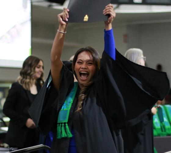 Graduate excited and holding up diploma at convocation