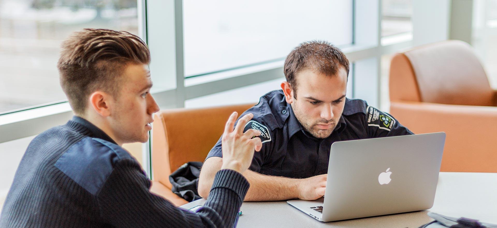 Two male Police Foundations students discuss a class project.