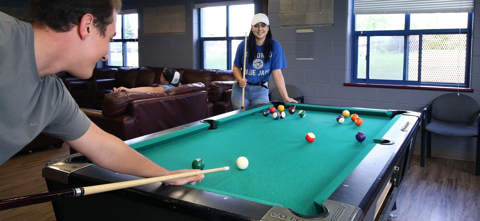 Two students playing pool on campus.