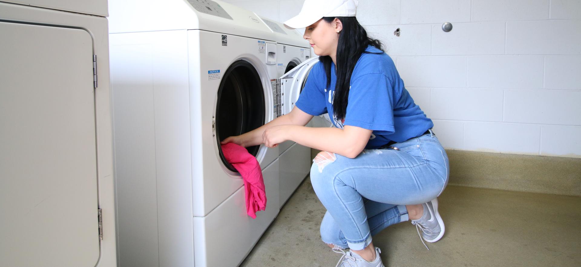 student putting clothes into washing machine