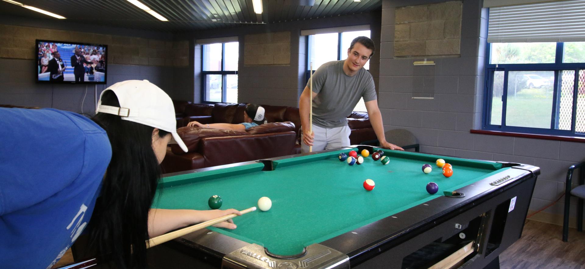 male and female students shooting pool in residence lounge