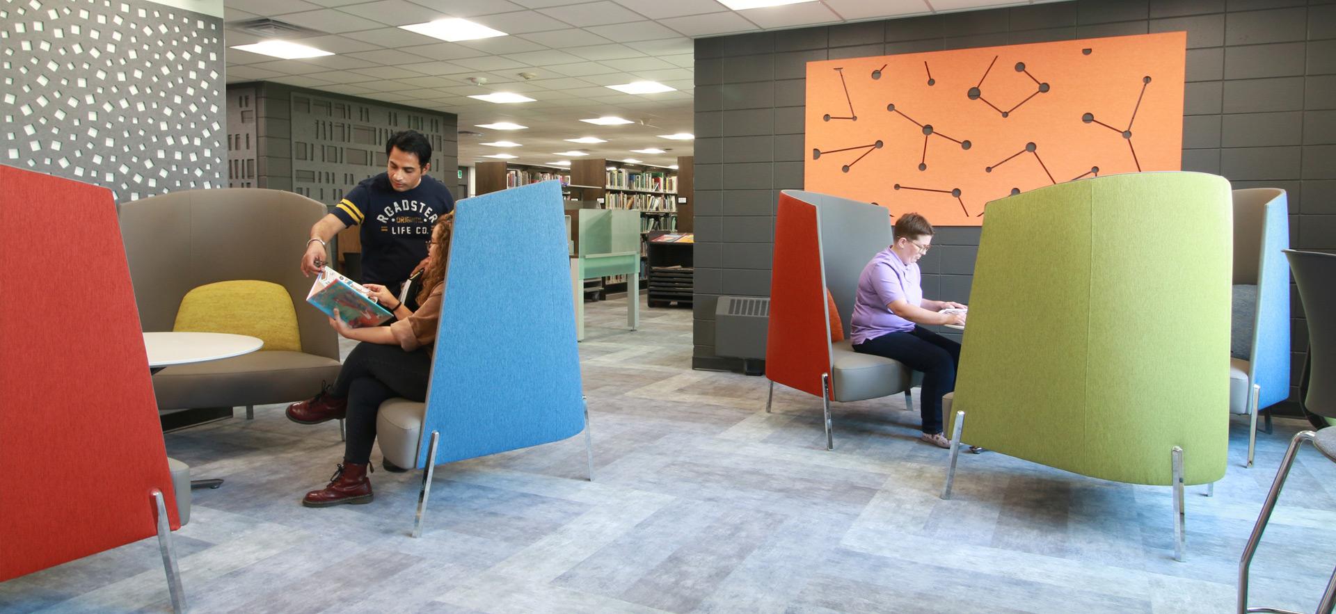 Students sitting in furniture within library 